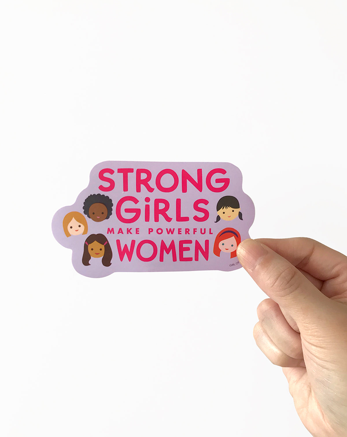 Vinyl sticker with 'Strong girls make powerful women' text held by a hand on a white background