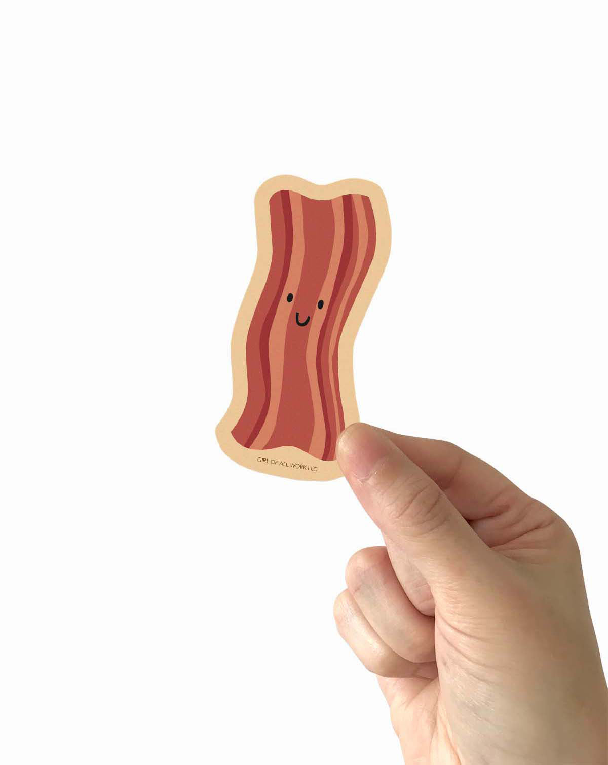 Hand holding a cute bacon vinyl sticker against a white background