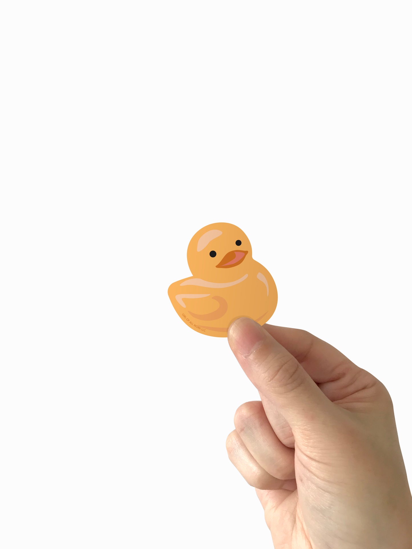 A hand holding a small yellow duck-shaped sticker against a plain white background.