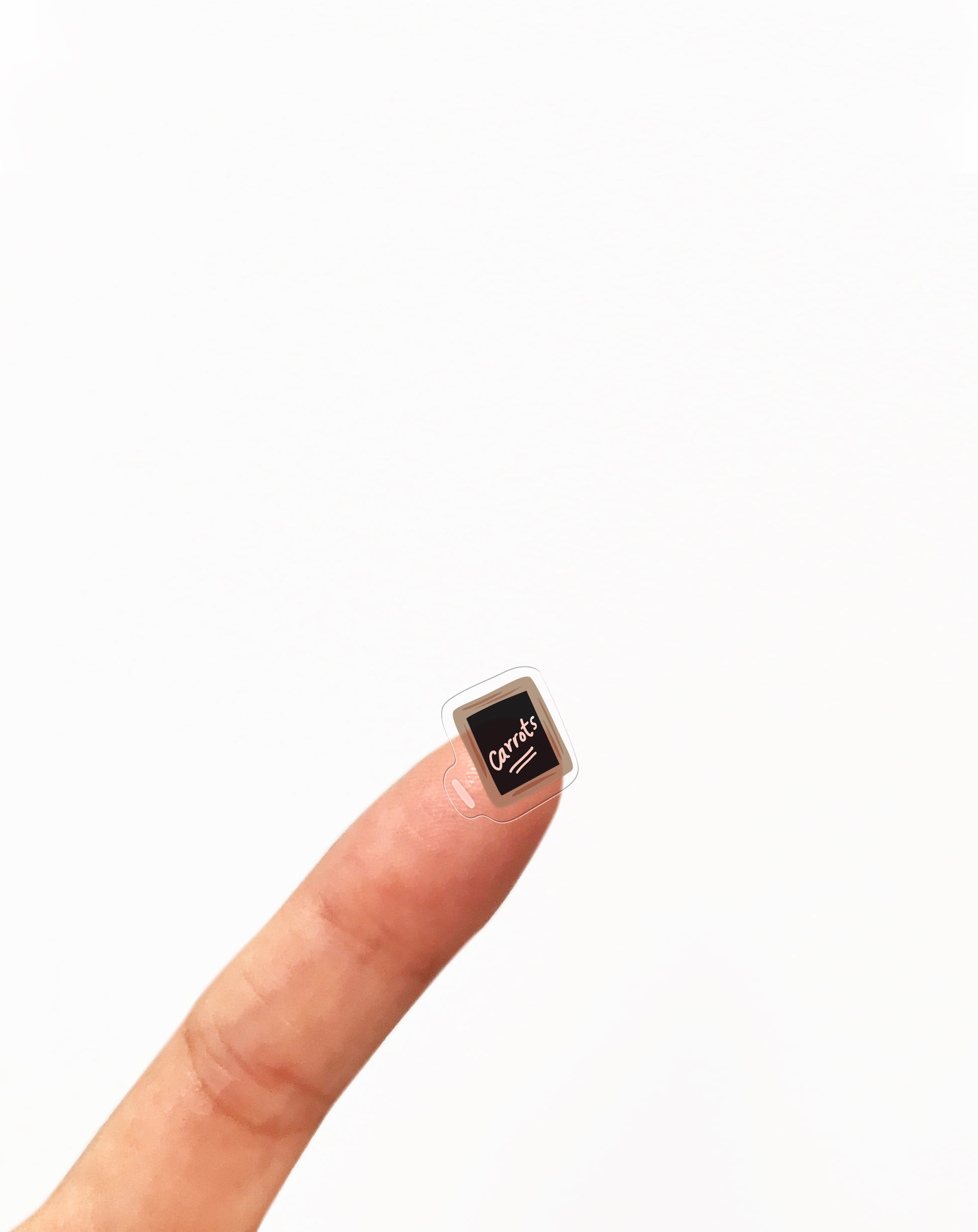 A finger holding a small clear sticker of chalk and slate 