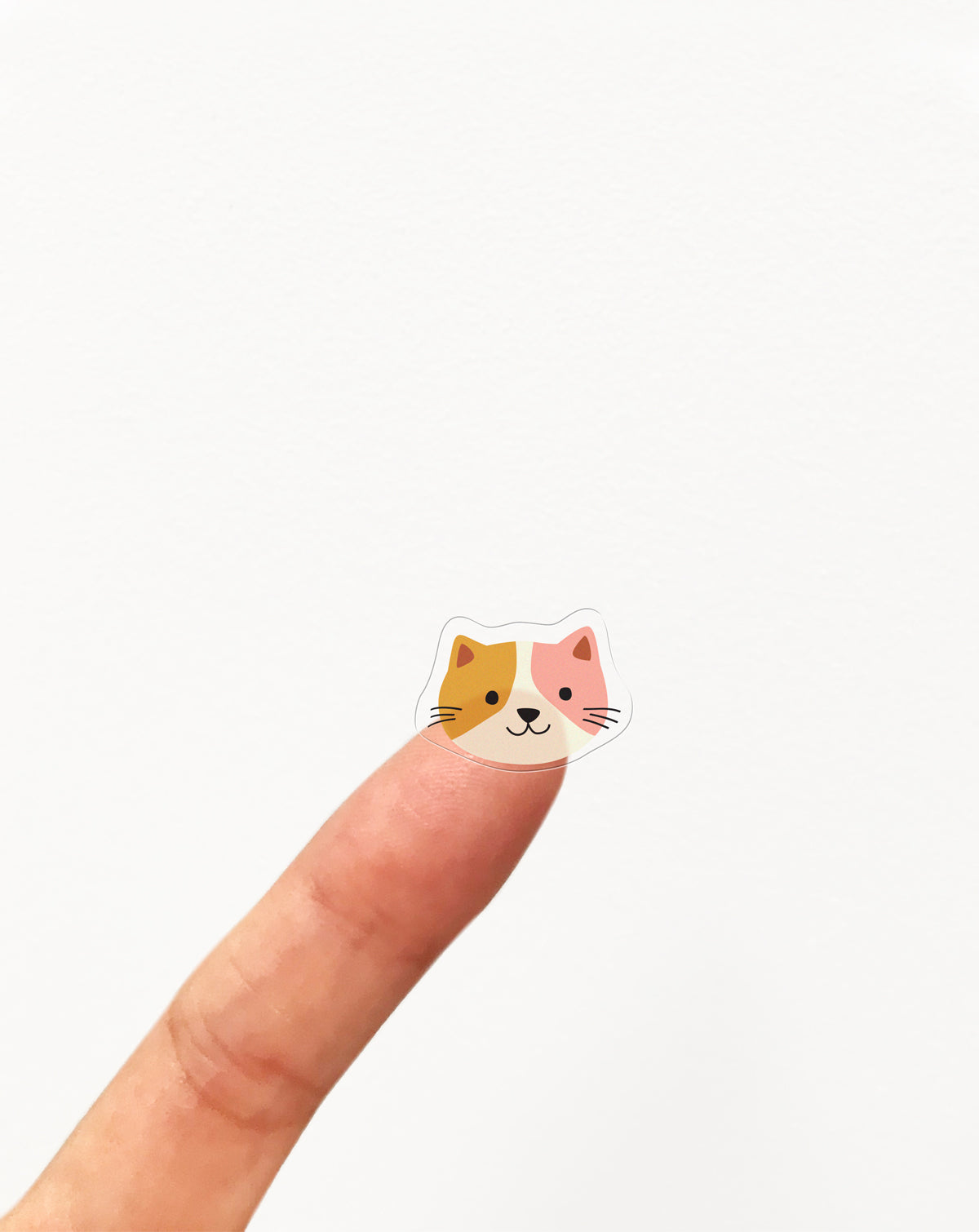 Sticker of a cat face on a finger against a white background