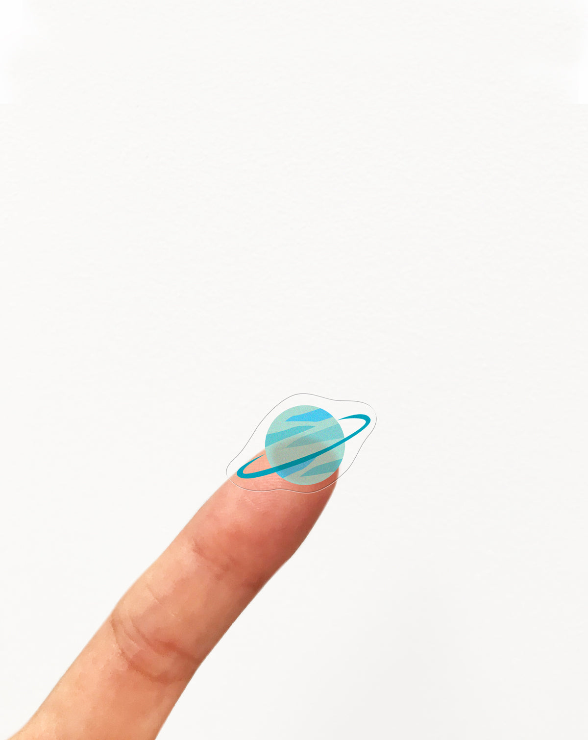 Clear planet sticker on a finger against a white background