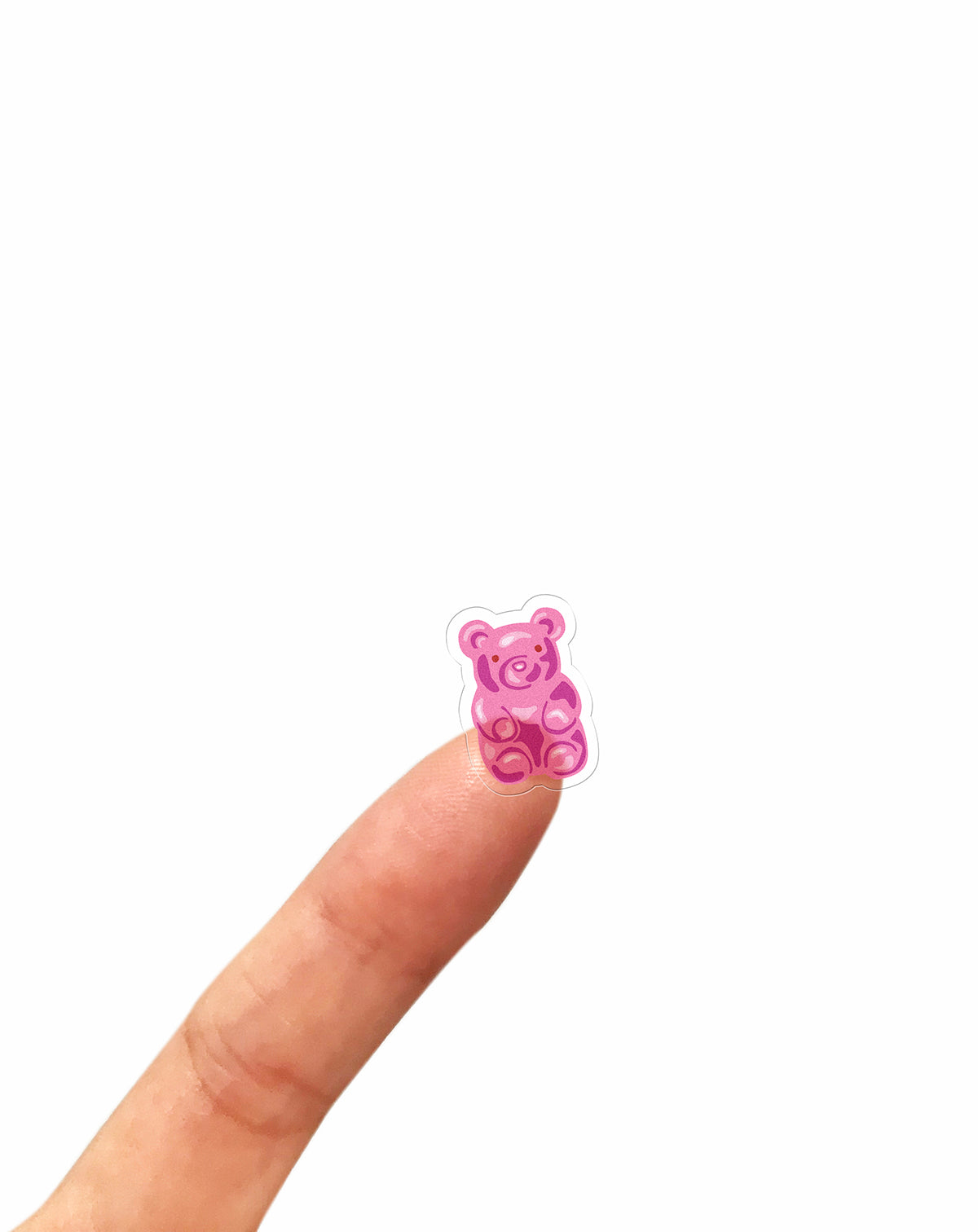 Pink clear gummy bear sticker on a person's finger against a white background