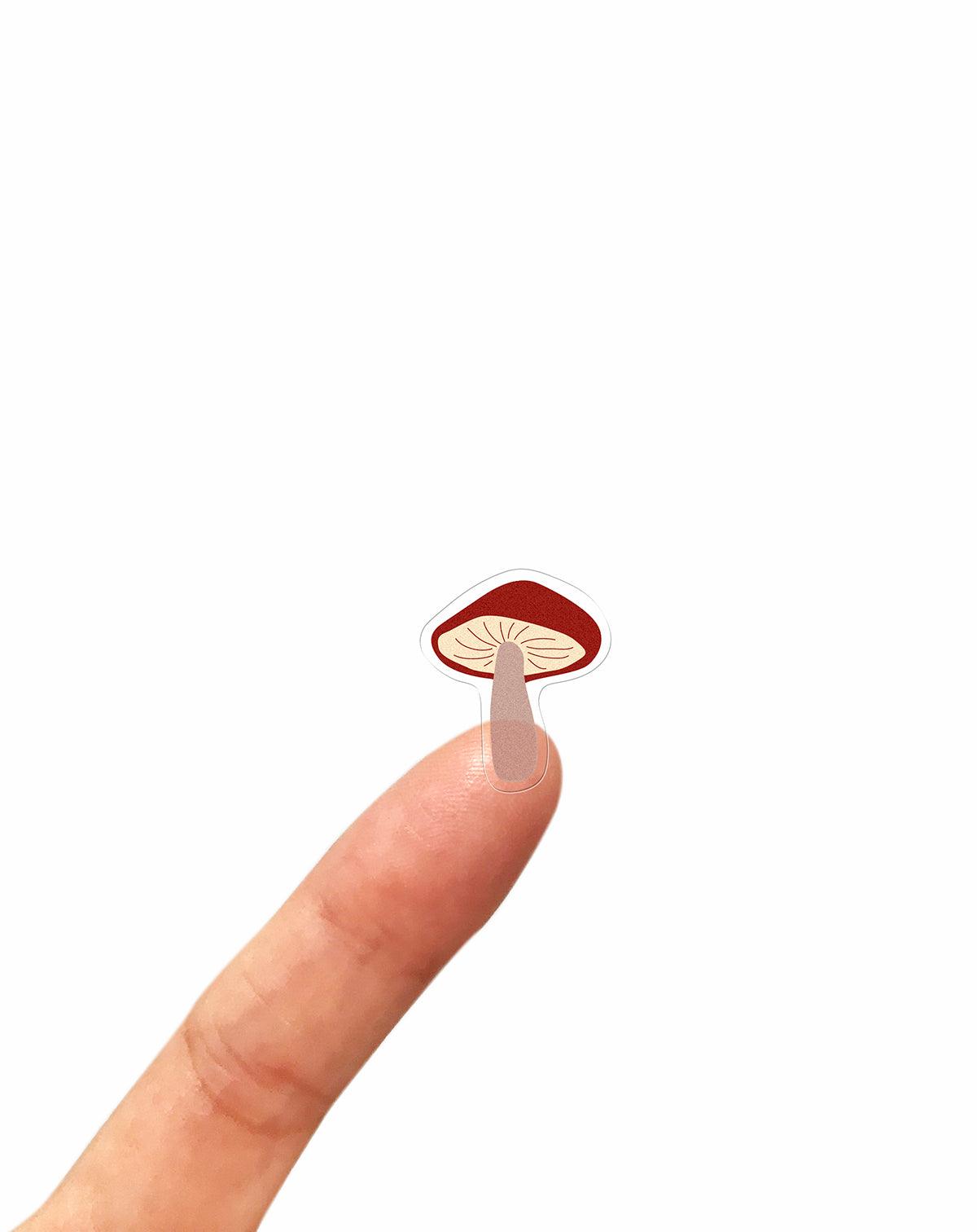 Mushroom-shaped clear sticker on a finger against a white background