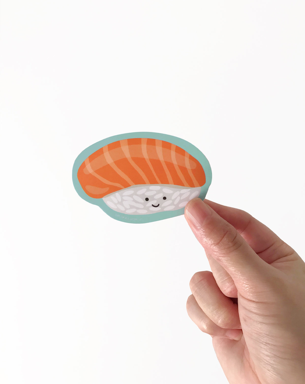 Hand holding a cute vinyl sticker with an  illustration of salmon sushi on a white background