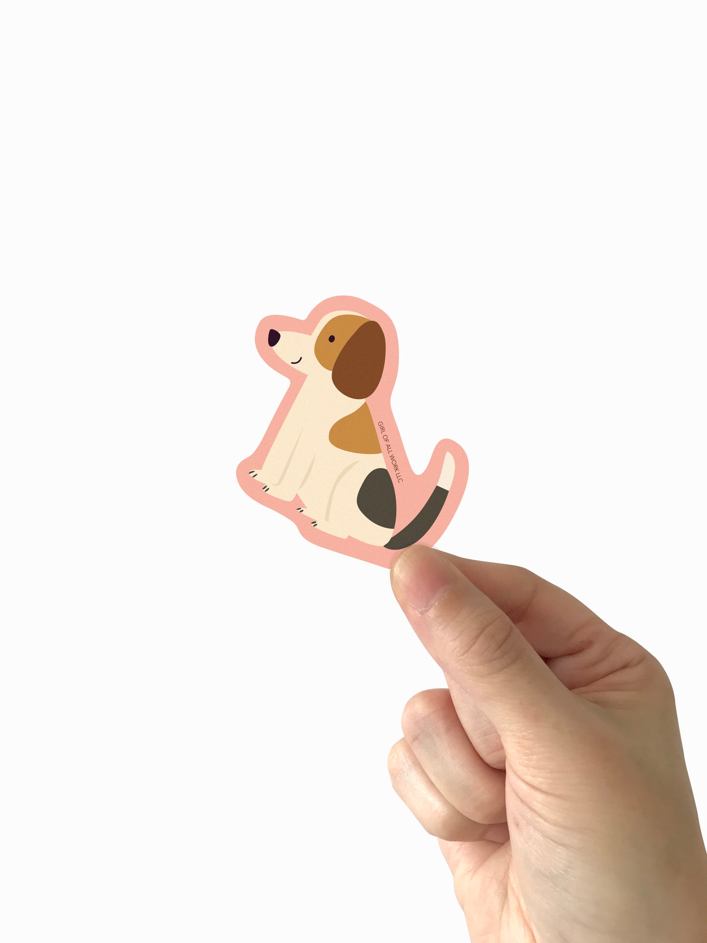 Hand holding a dog-shaped vinyl sticker against a white background