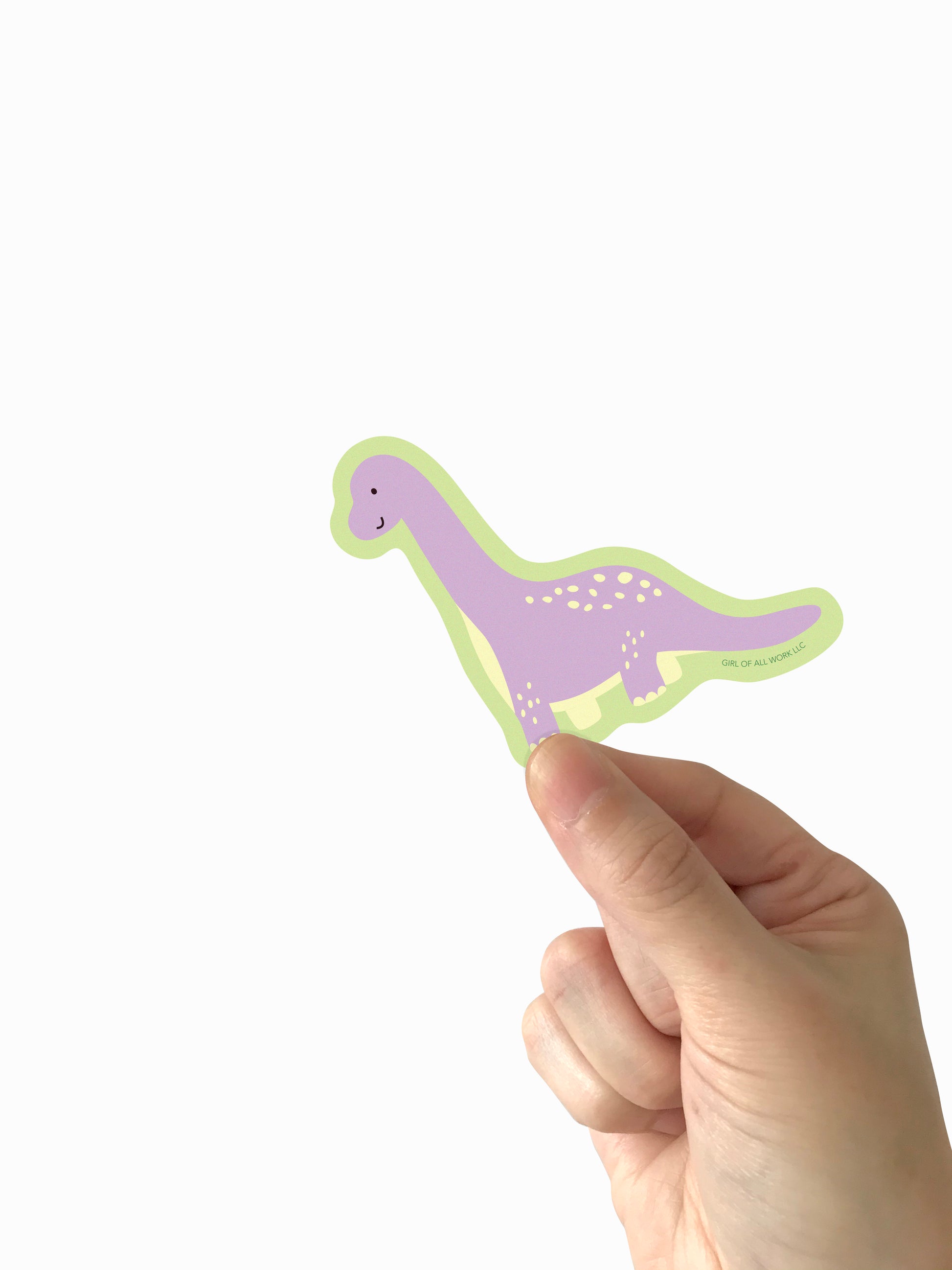 Hand holding a dinosaur-shaped vinyl sticker with a white background